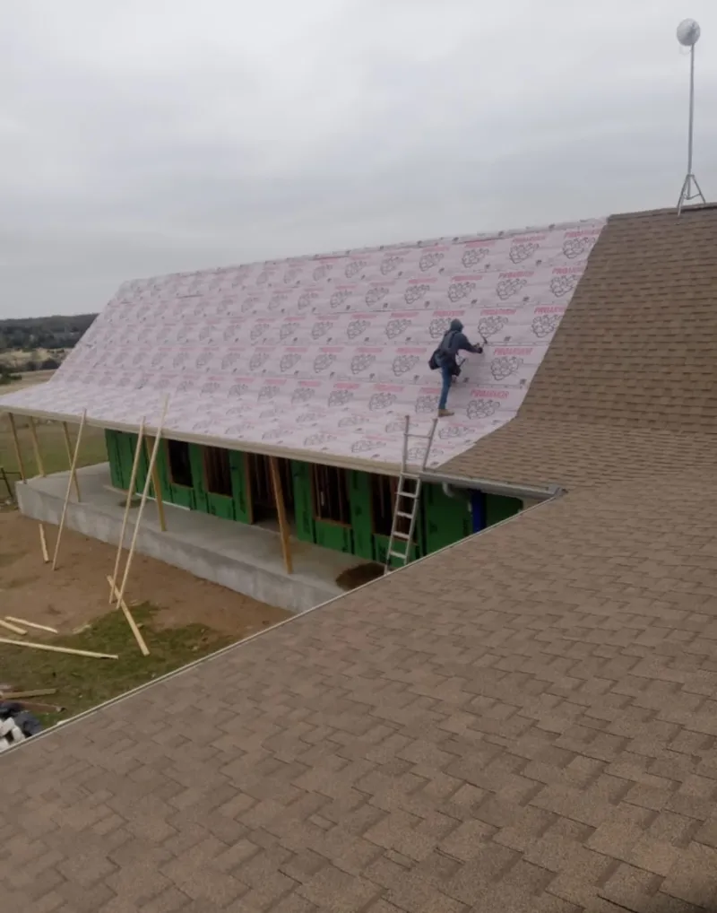 Worker preparing underlayment for a metal roof installation in Eden Prairie
